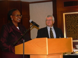 Philomena Mwaura addressing the May 27th Luncheon gathering. Mark Shaw in background